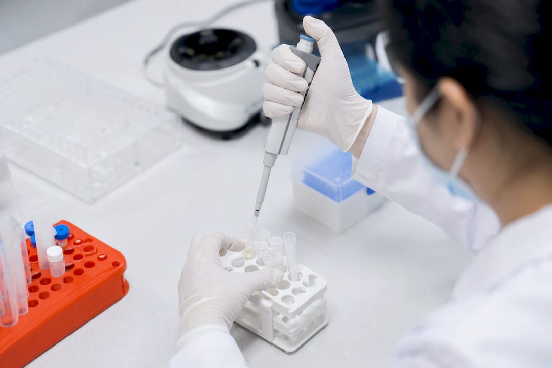 Gloved hand pipetting sample in drug testing lab