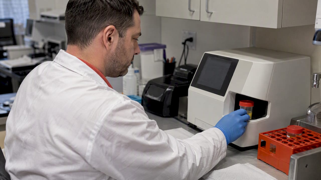 Technician loading urine sample for validity testing