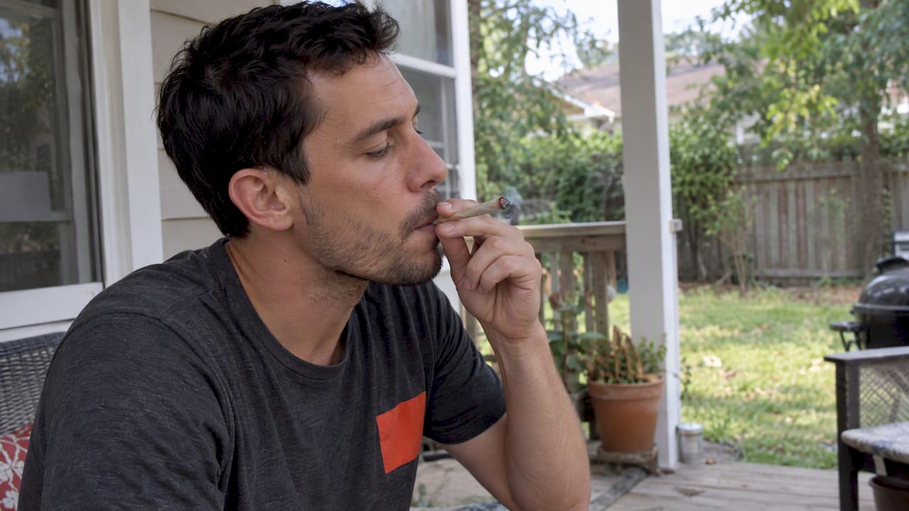 Man taking one draw from a cannabis joint