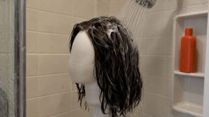 Woman washing hair with shampoo in shower